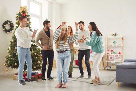 Group of friends celebrates New Year or Christmas by dancing to music during a party at home. The lively atmosphere brings joy and happiness as they enjoy the festive occasion together with laughter.の写真素材
