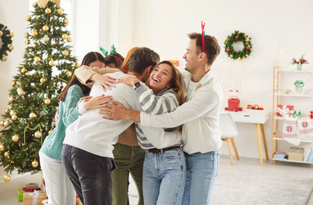 Crowd of friends embraces in celebration during a Christmas or New Year party at home. Moments of happiness, togetherness, and joy during the festive holiday celebration with a lively crowd.の写真素材