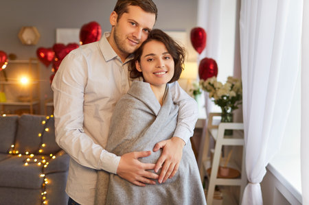 Photo of caring husband and wife stand closely to each other embrace and feel comfort celebrate St Valentines Day in cozy domestic atmosphere. Family, tederness and holiday conceptの写真素材
