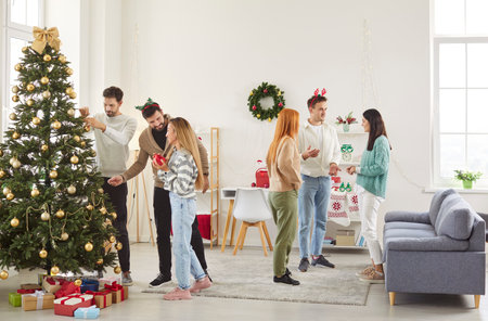 Company of friends celebrating Christmas or New Year at home, enjoying conversation and holiday fun. The festive party atmosphere brings joy and togetherness as they share moments of bonding.の写真素材