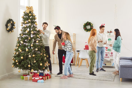 Full length photo of happy smiling people friends talking in living room together sharing news and stories gathering at New Year party at home. Christmas and winter holidays concept.の写真素材