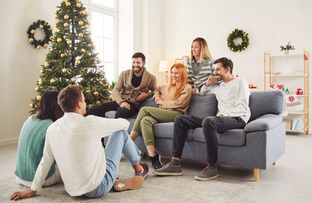 Diverse crowd of friends celebrates New Year or Christmas at a home party. The gathering fosters togetherness and holiday leisure, creating a joyful atmosphere for the festive season.の写真素材