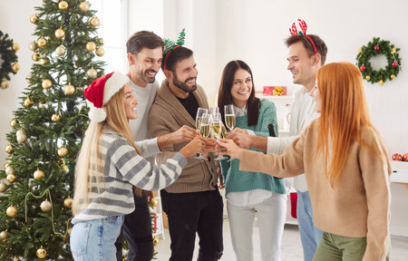 Friends raise champagne glasses in celebration during a New Year or Christmas party at home. The cheerful atmosphere and festive spirit fill the room as they toast and enjoy the holiday together.の写真素材