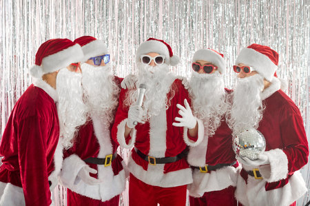 Happy funny people in Santa Claus red costumes having fun celebrating Christmas or New Year singing...