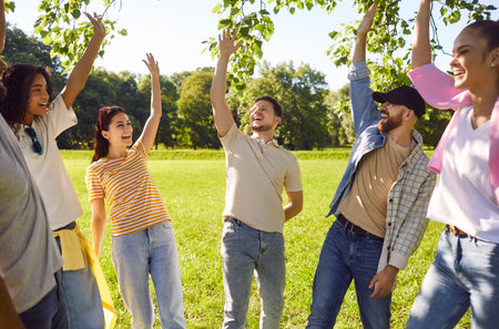 Portrait of a group of excited happy young friends students having fun hanging together outdoors in...