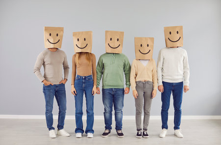 Positive thinking. Portrait of group of people wearing paper bags with smiling emoticons drawn on...