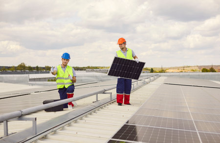 Workers installing and maintaining solar panels on the roof. The photovoltaic system provides...