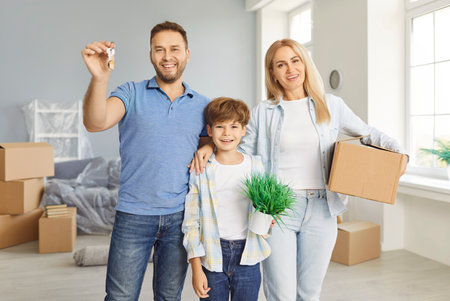 Portrait of a happy family with child holding keys to new home and looking at camera, celebrating...
