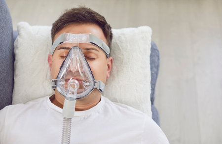 From above a young man with pneumonia or bronchitis wearing a medical oxygen breathing mask on his...
