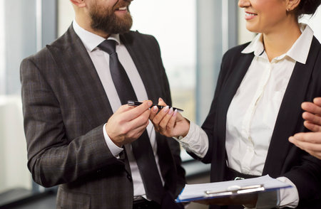 Cropped image of businessman giving pen to businesswoman for signing documents, affirming...