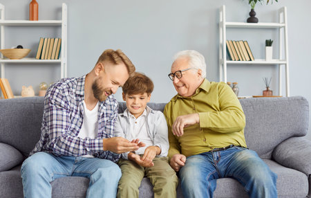 Grandfather, son, and father laughing together while spending leisure time on the couch at home...
