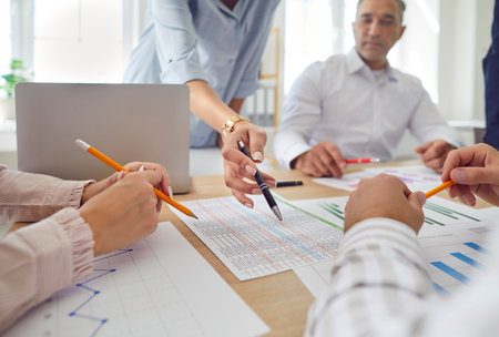 Office diverse staff workers close up, business people explaining project plan paperwork at group meeting, mentor training business team at corporate office briefing, checking financial documentsの写真素材