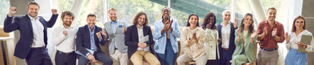 Happy audience applauding after a very good presentation at a business conference. Group of diverse people standing and sitting in a row, clapping hands and smiling. Banner, header. Success conceptの写真素材