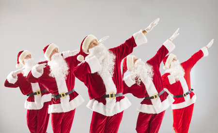 Happy New Year cute group dab dancing, partying wearing Santa Claus holiday costume, Merry Christmas red suits, celebrating festive season, gathered together enjoying lively and joyful partyの写真素材