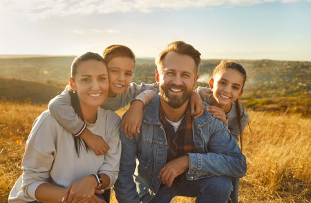 Group portrait of a positive smiling family with children, taking a leisurely walk, stroll in the nature. Perfect weekend or vacation, family togetherness and bonding on landscape background.の写真素材