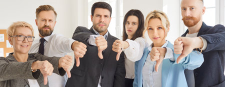 Business people team looks at camera showing thumbs down, dissatisfied face expression, dislike negative disagreement, disapproval, rejection, negative emotion, unsuccessful businessmen meetingの写真素材