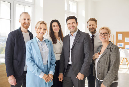 Happy smiling diverse professional business team standing in modern office, looking at camera, young and old teambuilding workers staff group together, human resource corporate portrait in officeの写真素材