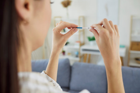Unknown woman checking pregnancy test, finding out about her future motherhood, getting possitive result, seeing two stripes, planning family. Fertility and happy expectations concept.の写真素材