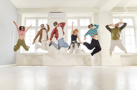Dance crew jumping high up in air, being full of energy, practicing new modern dance, celebrating...