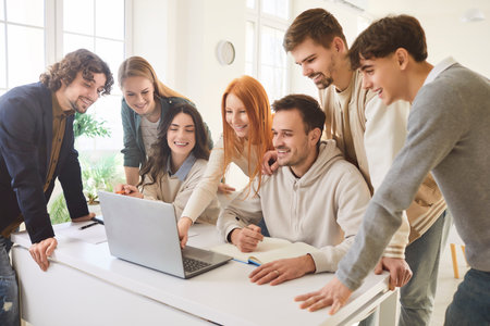 Young people discussing job project or new startup with brainstorming standing on workplace in office. Company employees or college students working with laptop. Teamwork and education concept.の写真素材