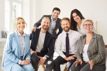 Group portrait of successful business team and company staff sitting and standing together in office space. Happy colleagues in smart casual suits smiling, posing for group photo, looking at camera.の写真素材