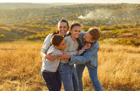 Overjoyed family embracing each other with love and have fun, laughing joyfully, posing in nature,...
