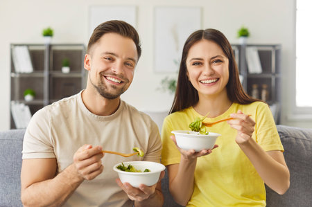 Takeaway food. Food delivery. Happy couple sharing at home eating healthy and nutritious meal and taste sensations from food. Healthy eating.の写真素材