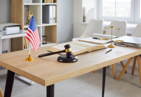 Closeup of modern office interior of judge or lawyer with wooden gavel and american flag on table....
