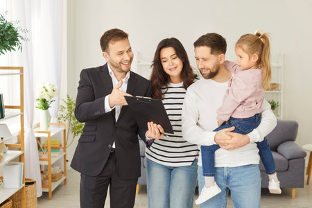 Real estate agent professional with happy family couple and child, young new homeowners in new modern apartment feeling joy about moving into new home, apartment rent, first house buying documentsの写真素材