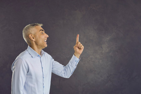 Smiling middle-aged Caucasian man raise finger up recommend good sale deal or promotion discount. Happy positive mature male point at blank empty copy space show offer, think of idea. Copyspace.の写真素材