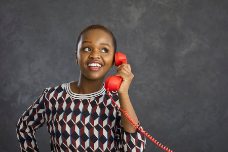 Happy young African American woman isolated on grey studio background talk speak on phone with...