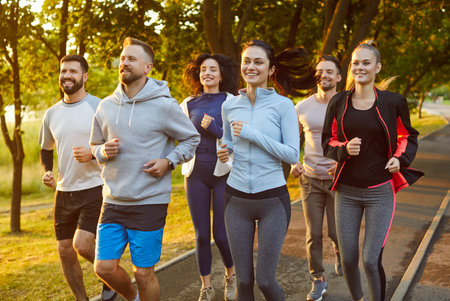 Positive runners team engages in running during group training outdoors, promoting sport, fostering group jogging, uniting people in a shared fitness run or jog across an invigorating landscape.の写真素材
