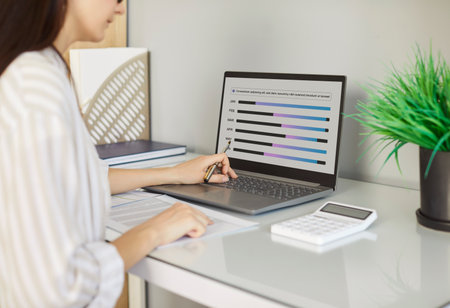 Portrait of a busy confident business woman accountant sitting at the desk with laptop analyzing company finances. Female employee working in office looking at computer monitor screen.の写真素材