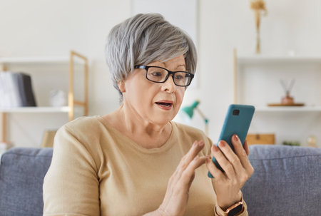 Annoyed senior old woman worry, elder phone user staring at screen in surprise of app error, data stealing, scam, bad family news, problems with smartphone, unable in using cell for video callの写真素材