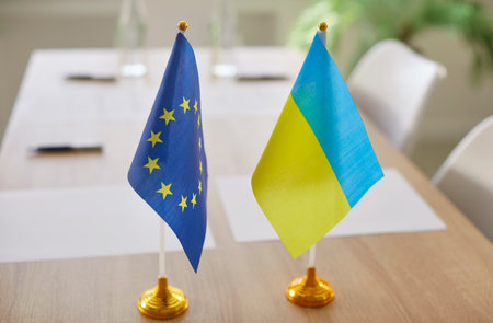 Flags of European Union and Ukraine standing on meeting table during political summit. Peaceful political dialogue focused on international security, economic development and strategic cooperation.の写真素材
