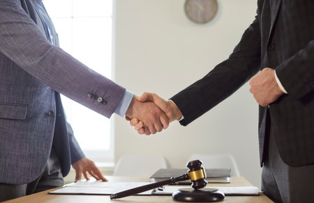 Close up photo of male lawyer in suit make a deal and shaking hand with a man client standing at the...