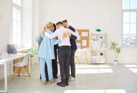 Diverse common people group gathered in circle hug at workplace office, share, psychological support, helping, plan strategy, interacting with sympathy on psychotherapy training, teambuilding gameの写真素材