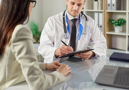 Doctor or nurse writing prescription for patient during medical appointment in hospital, healthcare advice and support, ensuring proper treatment during the visit and consultation.の写真素材