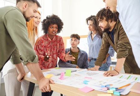 Team of colleagues collaborates on creating a business plan and management tasks and engaged in a conversation at the office. The meeting emphasizes teamwork and communication as they work together.の写真素材