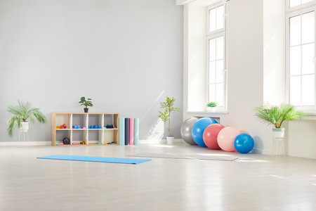 Interior of empty fitness gymnasium for yoga classes with sport equipment of fit balls and mats on the floor. Panoramic view of rehabilitation gym in medical clinic for physical treatment.の写真素材