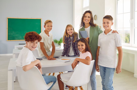 Happy smiling children and woman teacher look at camera during class. Group of male and female...