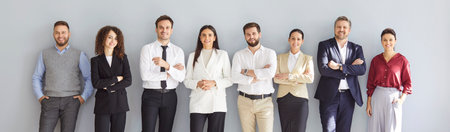 Group of confident cheerful business people men and women looking at camera and smiling on gray wall...