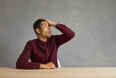 Embarrassed young african american man keeps his hand on his forehead remembering that he forgot to...