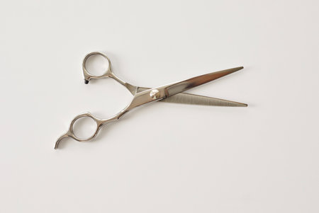 Stainless steel hairdressing scissors with ergonomic finger rests placed diagonally on a clean white...