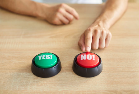 Unrecognizable male chooses between green YES and red NO buttons on wooden table. Young man makes...
