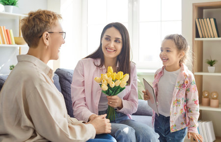 Little daughter anf her adult mother congratulating grandmother with Women Day or Mothers Day,...