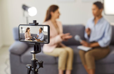 Video interview with influencer, live podcast recording for social media with smartphone camera on...
