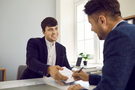Two people meet in the office and sign a business contract. Friendly man who works as a manager,...
