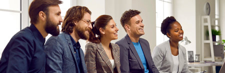 Multicultural happy peoples men and women sits in row watching presentation or speech by colleague...