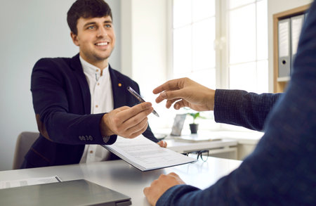 Two happy people meet in the office, make a business deal and sign a contract agreement. Friendly...